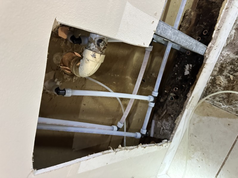 PEX plumbing behind wall with copper fittings