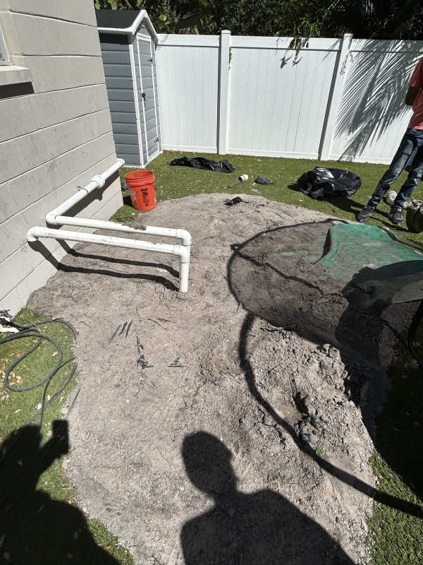 Finalized plumbing trench backfilled with visible exterior pipes