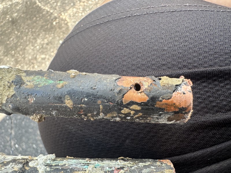 Plumber cutting out damaged copper pipe to prepare for manifold replacement