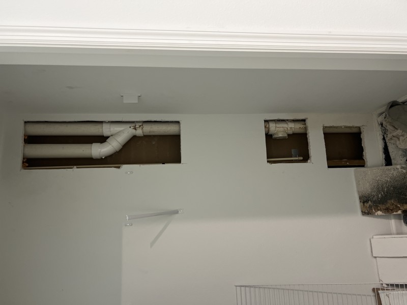 Exposed pipe joint inside wall showing visible crack and water damage