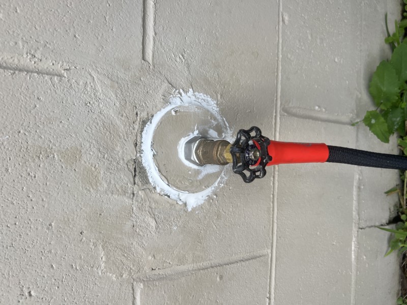 Completed hose bib repair with stucco patch and texture blending for a seamless exterior finish