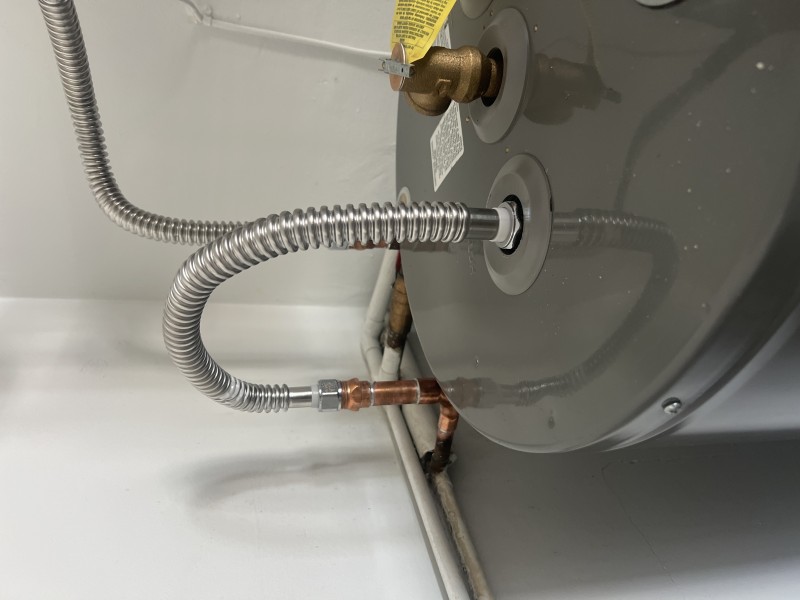 Plumber inspecting galvanized nipple and preparing replacement on water heater