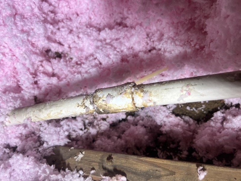 Plumber repairing a cracked 3/4 inch PVC pipe in an attic using couplings and solvent cement