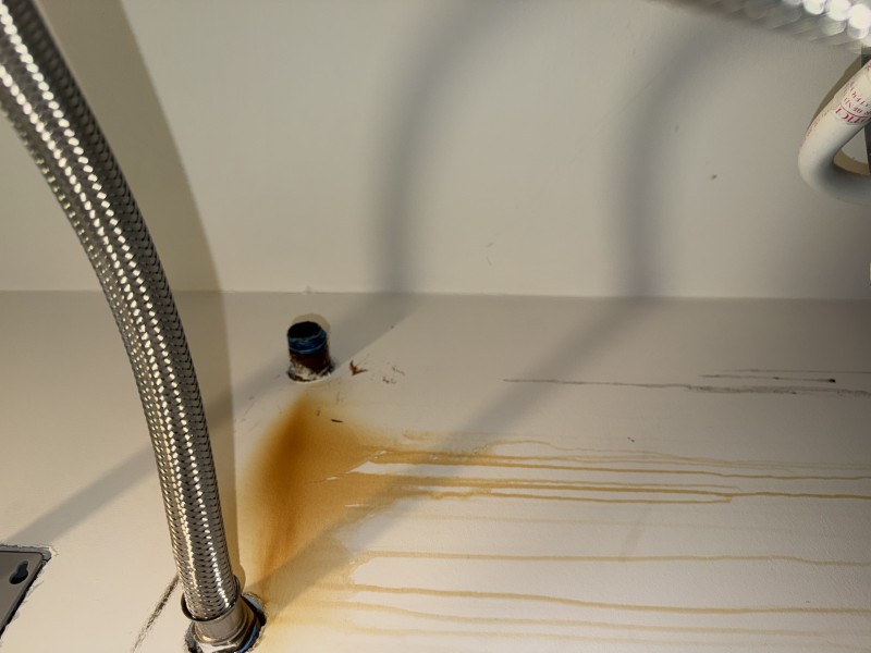 Plumber disconnecting flex line and ball valve from a corroded galvanized nipple above a water heater