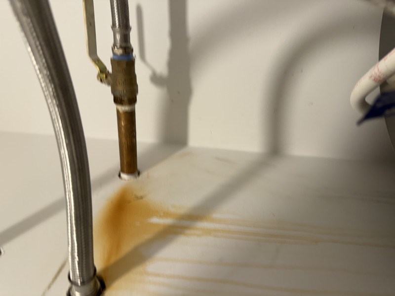 New brass nipple installed with reconnected cold water line and ball valve above a residential water heater