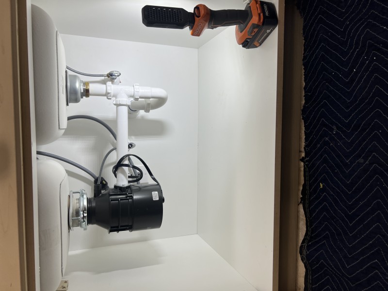 Completed under-sink drain assembly with white plastic P-trap and garbage disposal connection, Tampa FL, January 2026