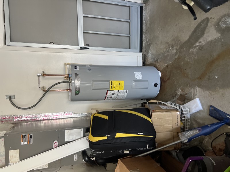 New electric water heater positioned for installation in the garage near supply piping, Tampa, FL, January 2026