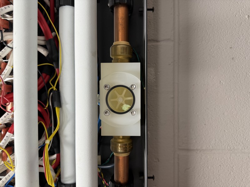 Close-up service work around tankless water heater flow sensor housing and water pathway components, Tampa, FL, January 14, 2026