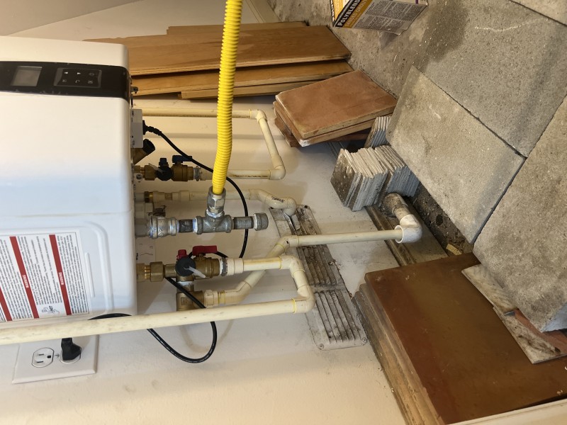 Gas flex connector, shutoff, and service-ready plumbing connections at the Navien tankless unit, Tampa, FL, February 2026