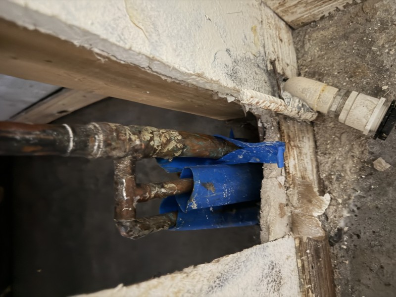 Concrete slab opened exposing vertical copper piping and blue protective wrap, Riverview FL, February 26 2026