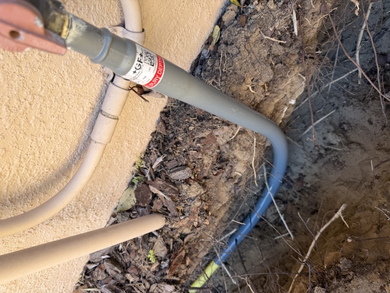 New 3/4-inch gas riser and coated gas line entering the trench beside the exterior wall, Davenport, FL, March 2026