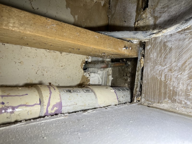 Vertical copper and PVC plumbing lines near wall cavity used for line tracing and manifold diagnosis, Tampa, FL, March 2026