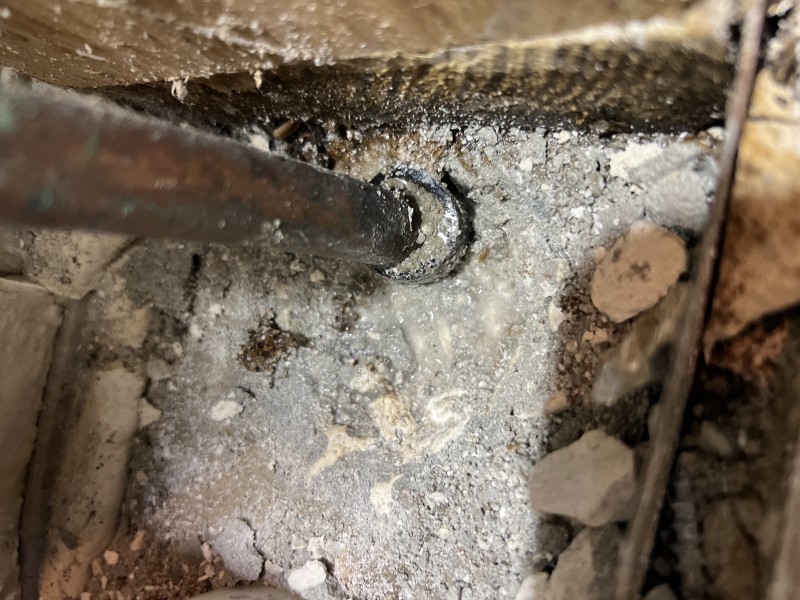Close-up of copper pipe entering slab with surrounding concrete debris indicating leak origin, Tampa, FL, March 2026