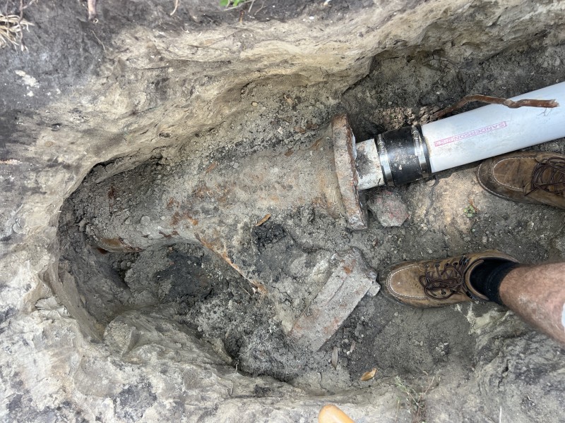 Technician inspecting exposed cast iron wye fitting inside trench, Florida, March 2026