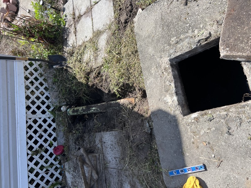 Open excavation pit exposing the main drain access hole and depth of the underground sewer line — Polk City, FL, April 2026
