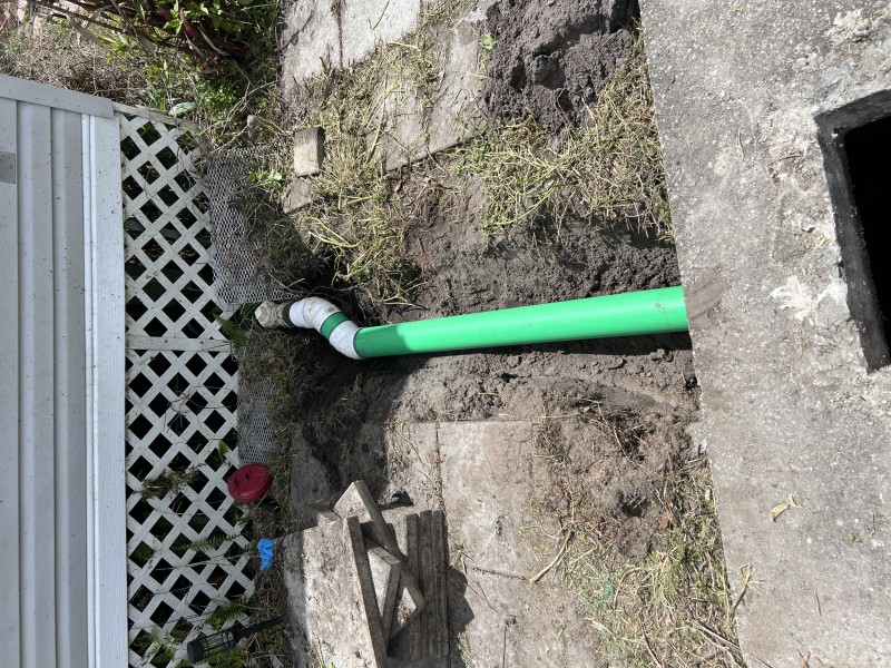 New Schedule 40 green PVC main drain pipe installed in excavated trench with proper slope and rubber coupling fittings — Polk City, FL, April 2026