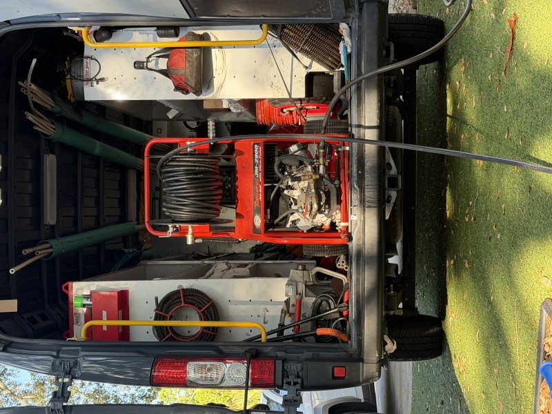 Service truck loaded with red professional hydro jetting machine and hose reel used for high-pressure sewer line cleaning, South Tampa FL, April 2026