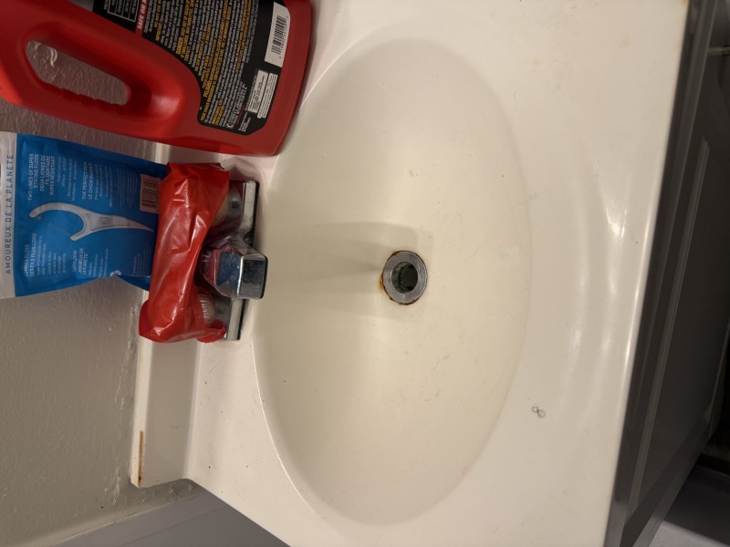 Top-down view of completely clogged white porcelain bathroom sink lavatory with standing water and slow drain, Tampa FL, April 2026