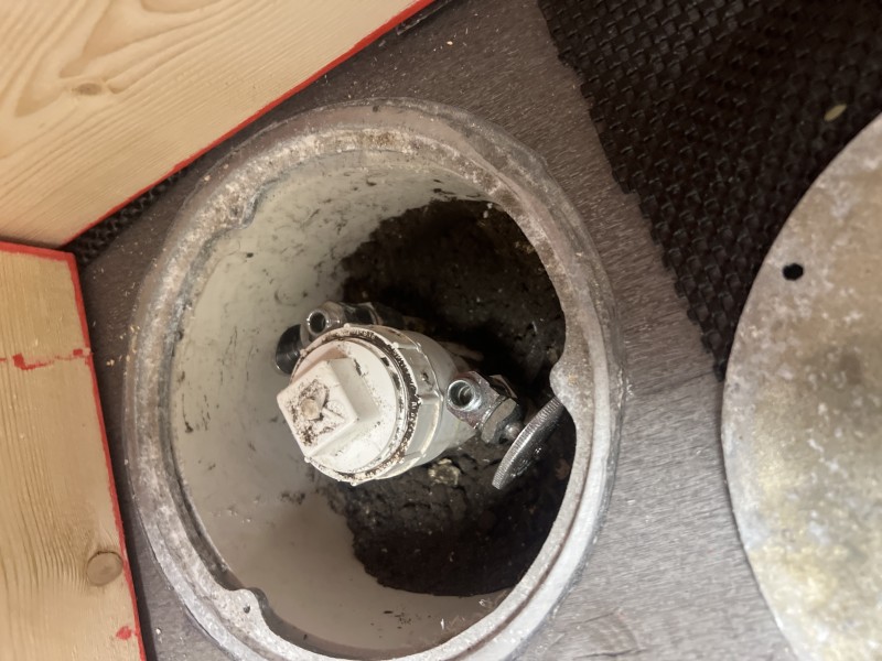 Close-up top-down view into pedicure drain flange hole showing new supply valve fitting installed through the platform floor, Tampa FL, May 2026