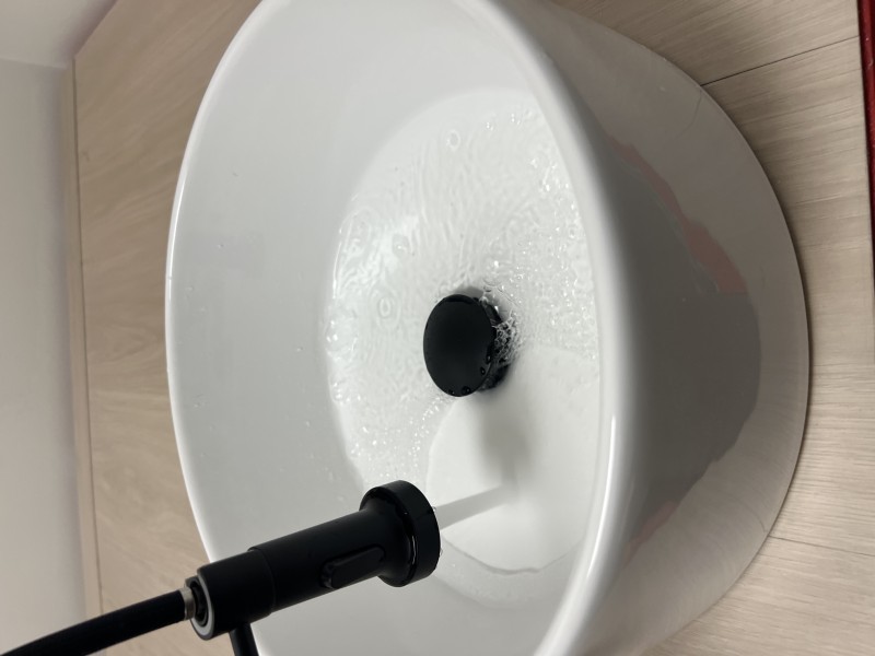 Overhead view of completed pedicure station showing white ceramic basin and black matte faucet installed on wood-finish platform with red trim edges and AAV vent visible at front base, Tampa FL, May 2026
