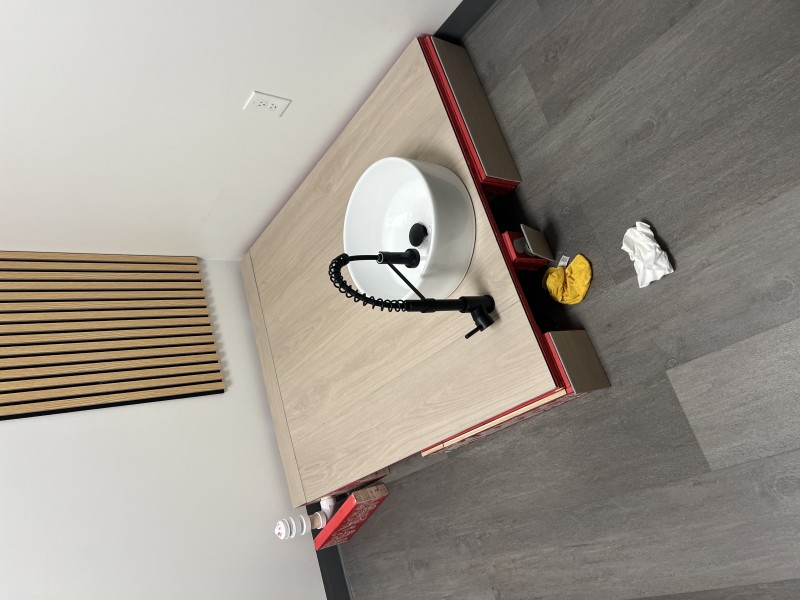Close-up of white pedicure basin with water running and pooling during final flow test, showing black matte drain stopper and faucet spout confirming successful installation, Tampa FL, May 2026
